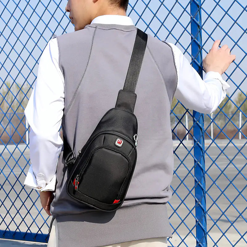 Sport shoulder bag with headphone jack in black, worn by person in outdoor setting.