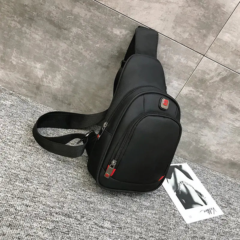 Sport shoulder bag with headphone jack, black, on gray carpet, single strap, sleek design.